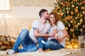 Happy family of mother, father and little baby girl hugging and kissing near Christmas tree Royalty Free Stock Photo