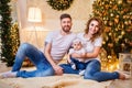 Happy family of mother, father and little baby girl sitting near Christmas tree on the floor Royalty Free Stock Photo