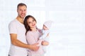 Happy family, mother and father standing with baby home in white room near window Royalty Free Stock Photo