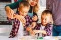 Happy family of mother, father and two children twins sons bake cookies in kitchen before Christmas