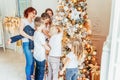 Happy family mother and five children decorating Christmas tree on Christmas eve at home. Mom daughters sons in light