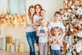 Happy family mother and five children decorating Christmas tree on Christmas eve at home. Mom daughters sons in light room with