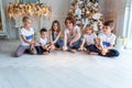 Mother and five children playing sparkler near Christmas tree at home