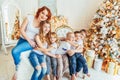 Happy family mother and five children relax playing near Christmas tree on Christmas eve at home. Mom daughters sons in