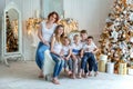 Mother and five children near Christmas tree at home