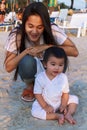 Happy family Mother and her little daughter play at the beach together. Happy little girl relax and sit on the beach with her Royalty Free Stock Photo