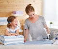 Happy family mother housewife and child daughter ironing clothes Royalty Free Stock Photo