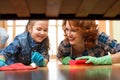 Happy family mother and kid daughter clean room at home. Middle-aged woman and little child girl wiped floor under bed Royalty Free Stock Photo