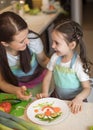 Happy family mother and kid girl are preparing healthy food, they improvise together in the kitchen Royalty Free Stock Photo