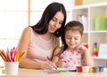 Happy family mother and kid daughter together paint. Woman helps child girl. Royalty Free Stock Photo