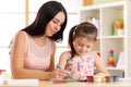 Happy family. Mother and kid daughter together paint. Woman helps to child girl. Royalty Free Stock Photo