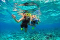 Mother, kid in snorkeling mask dive underwater with tropical fishes