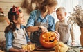 Happy family mother and kids carving pumpkin for Halloween holiday together at home Royalty Free Stock Photo