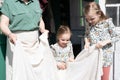 Happy family mother with little kids daughters helper girls have fun in suburb countryside life on sunny laundry day. candid mom a Royalty Free Stock Photo