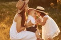 Happy family of mother, little son and daughter spending free time on the field at sunny day time of summer Royalty Free Stock Photo