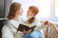 Happy family mother reads book to child to daughter by window Royalty Free Stock Photo