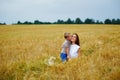 Happy family of mother and son in a summer wheat field. The boy kisses his mother