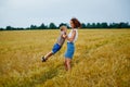 A happy family of mother and son in a summer wheat field. A woman holds her son in her arms and circles Royalty Free Stock Photo