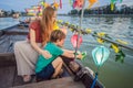 Happy family Mother and son of travelers ride a national boat on background of Hoi An ancient town, Vietnam. Vietnam