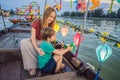 Happy family Mother and son of travelers ride a national boat on background of Hoi An ancient town, Vietnam. Vietnam