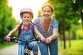 Happy family mother teaches child daughter to ride a bike in the Park