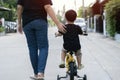 Happy family mother teaches her child to ride a bike on the street at the village park Royalty Free Stock Photo