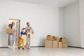 Happy family with moving boxes entering in new apartment. Settling into home