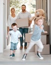 Happy family moving into new house. Excited children running into their new house. Family carrying boxes, moving into Royalty Free Stock Photo