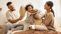 Happy multiethnic family mom, dad and child  laughing, playing, fights pillows and jumping in bed   at home Royalty Free Stock Photo