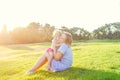 Happy family on nature. Mom and toddler baby daughter relaxing, hugging, laughing and have fun on green grass meadow at evening su Royalty Free Stock Photo