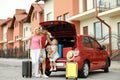 Happy family near car trunk with suitcases