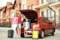 Happy family near car trunk with suitcases