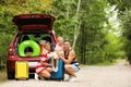 Happy family near car trunk with suitcases outdoors