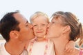 Happy family near to sea, parents kiss daughter