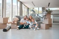 Happy family in a new home, sitting on the floor with children. Portrait of young caucasian parents with two sons Royalty Free Stock Photo