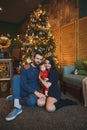 Happy family new year photo session: mother, father and little child are sitting near the new year tree Royalty Free Stock Photo