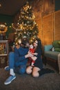 Happy family new year photo session: mother, father and little child are sitting near the new year tree Royalty Free Stock Photo