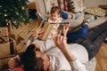 Happy family on new year`s eve spends time at home, man and woman lie on the floor near a decorated Christmas tree
