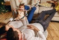 Happy family on new year`s eve spends time at home, man and woman lie on the floor near a decorated Christmas tree