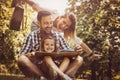 Happy family with one child in meadow reading book together. Royalty Free Stock Photo