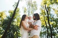 Happy family on the open air. Young dark-haired woman and her husband are kissing their charming little daughter.