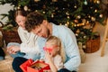 Happy family opening gifts while sitting on floor near Christmas tree Royalty Free Stock Photo