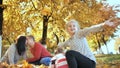 Happy family outdoors playing with fallen leaves in sunny autumn weather. Parents kiss in the background. Royalty Free Stock Photo