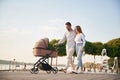 Happy family outdoors. A young couple with a baby pram is walking together Royalty Free Stock Photo