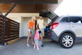 Happy family packing things to car at home parking Royalty Free Stock Photo