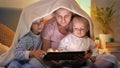 Happy family in pajamas playing games on tablet computer at night. Family having time together, parenting, happy childhood and Royalty Free Stock Photo