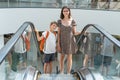 A happy family with paper bags is standing on an escalator in a shopping mall and discussing their purchases Royalty Free Stock Photo