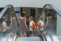 A happy family with paper bags is standing on an escalator in a shopping mall and discussing their purchases Royalty Free Stock Photo