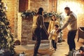 Happy family parents with two kids dancing together near fireplace and xmas tree in cozy countryhouse decorated for Christmas Royalty Free Stock Photo