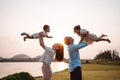 Happy family in the park sunset light. family on weekend playing together in the meadow with river Parents hold the child and Royalty Free Stock Photo